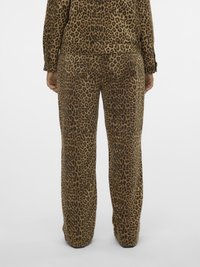 Persona che indossa una giacca e pantaloni a gamba dritta con stampa leopardata coordinata, in piedi davanti a uno sfondo chiaro uniforme, vista da dietro.