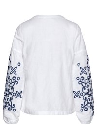 Top bianco in lino con lunghe maniche a sbuffo, caratterizzato da ricami floreali blu navy intricati sulle maniche. Scollo rotondo semplice, vestibilità morbida.
