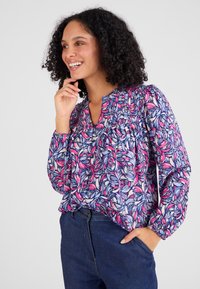 Langarm blouse in een bloemenpatroon met roze, blauw en wit. V-hals met plooien en elastische manchetten; losse pasvorm.