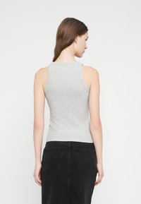 Γκρι αμάνικη μπλούζα με εφαρμοστή γραμμή και στρογγυλή λαιμόκοψη, συνδυασμένη με μαύρη τζιν φούστα με τσεπάκια στην πλάτη.