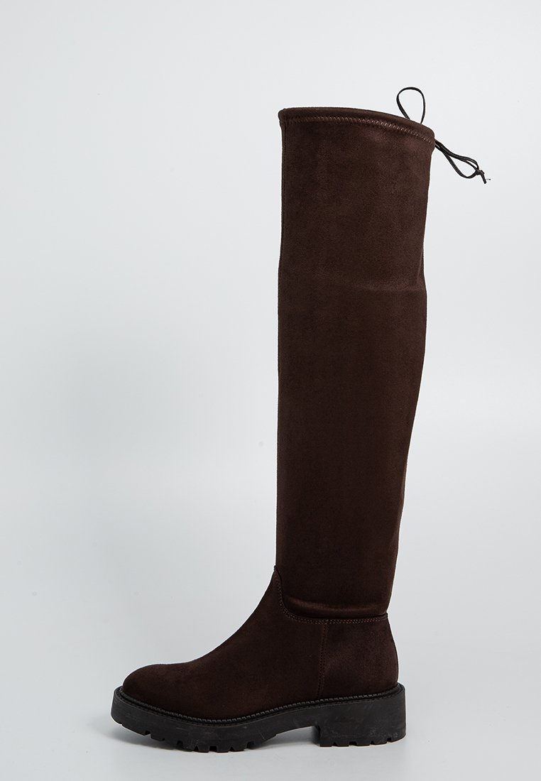 Alti stivali in suede marrone con punta tonda, suola spessa in gomma e dettagli di laccio nella parte superiore. Texture liscia e design aderente.