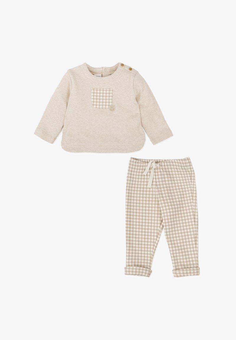 Haut beige à manches longues avec une poche de patch à carreaux et deux boutons à l'épaule, associé à un pantalon beige à carreaux avec une taille à cordon.