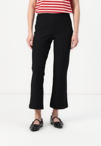 Black cropped pants with a straight leg design, featuring a smooth texture and front seams, paired with black dotted shoes. Red and white striped top.