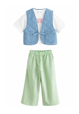 Gilet matelassé bleu clair avec deux poches avant, associé à un t-shirt blanc avec des lettres rouges, et un pantalon large rayé vert et rose.