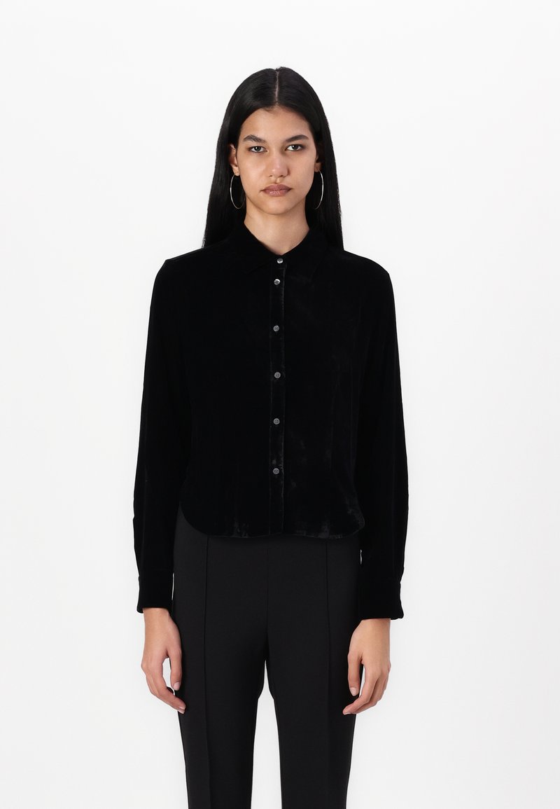 Mustast sametist pika varrukaga särk, millel on nööpidega esikülg, kaelus ning peene sädelusega, koos sobivate mustade pükstega.