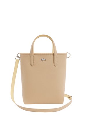Beige gestructureerde leren handtas met kleine handvatten, afneembare lange schouderriem en klein zilveren krokodillenlogo aan de voorkant.