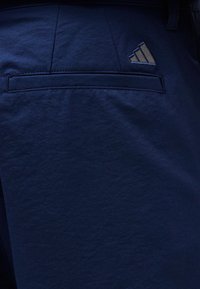 Υφασμα σκούρου ναυτικού μπλε με οριζόντια ραφή τσέπης και μικρό κεντημένο λογότυπο με τρεις διαγώνιες ρίγες.