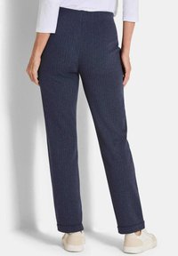 Marineblauwe visgraatpatroon broeken met een rechte pasvorm, een middelhoge taille en opgerolde manchetten, gecombineerd met lichtgekleurde sneakers.
