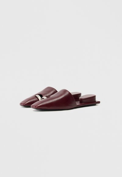 Burgundy leather mules with a pointed toe, open back, and a metallic accent in the center. Smooth texture and flat sole design.