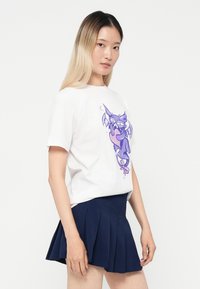 White cotton t-shirt featuring a purple illustrated character print, paired with a dark navy pleated skirt.