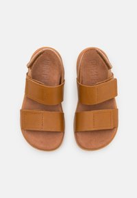 Hnědé kožené sandály s dvěma nastavitelnými pásky na suchý zip, měkkou semišovou vložkou a plochou gumovou podrážkou. Jednoduchý design, otevřená špička.