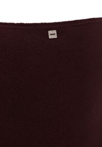 Burgundy textile with a soft, plush texture; features a small silver logo tag at the top. Overall simple design.