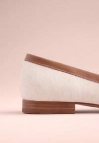 Chaussure à enfiler en cuir et tissu tissé avec une tige beige et des garnitures en cuir marron, dotée d'un petit talon en bois. Texture lisse et design minimaliste.