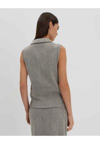Blusa grigia e nera senza maniche con un colletto a punta, caratterizzata da una vestibilità dritta e un motivo sottile, progettata per una silhouette aderente.