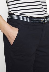 Námořnické bavlněné kalhoty se bočními kapsami, s pruhovaným tkaným opaskem v námořnické a světle modré barvě se zlatou sponou.