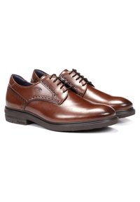 Zapatos de cuero marrón con un acabado liso, detalles de brogue en la parte superior, puntera redonda y suela de goma negra. Diseño de cordones para un ajuste seguro.