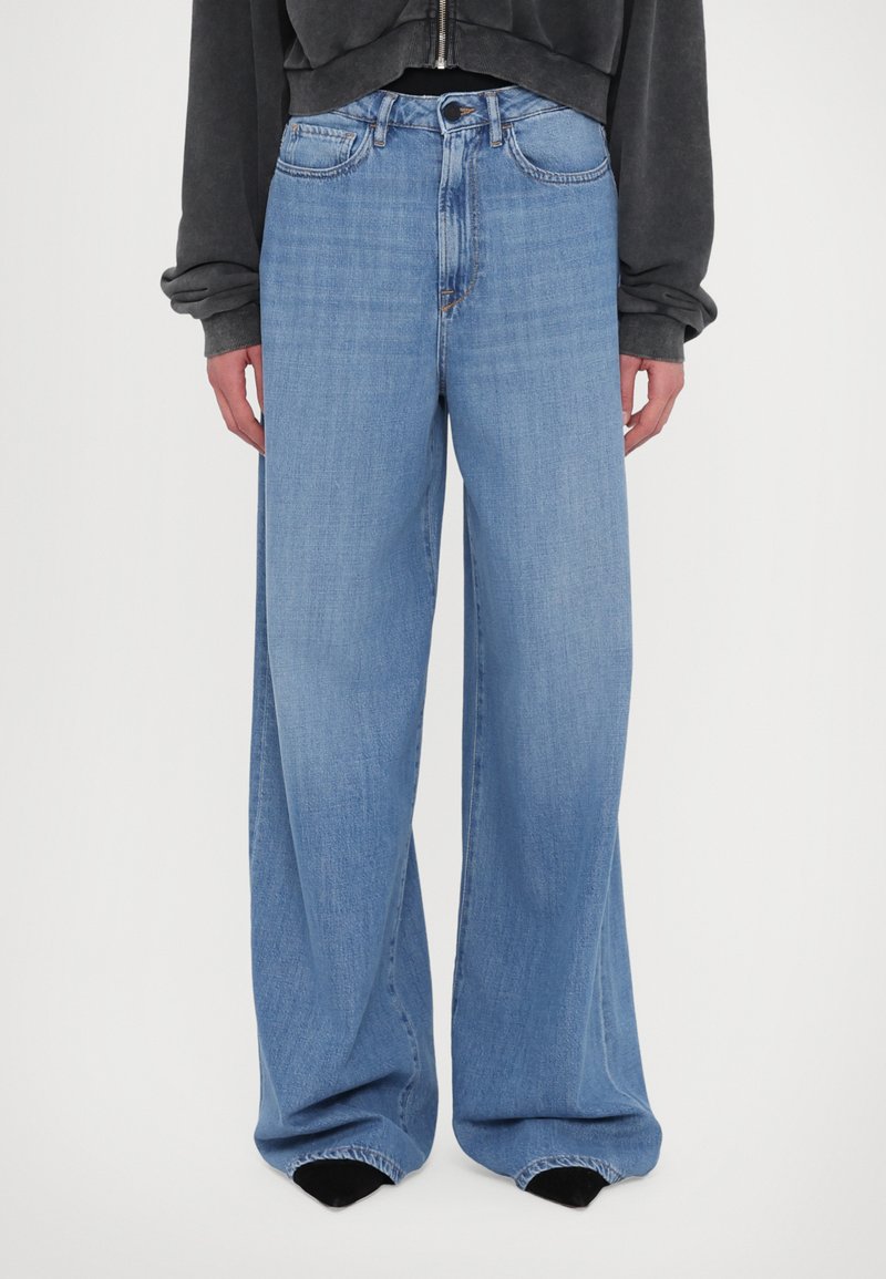 Hellblaue, weite Jeans aus Denim. Hohe Taille mit traditionellem Fünf-Taschen-Design. Verfügt über einen Knopf- und Reißverschluss.