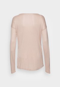 Light pink long-sleeve top with a wide neckline, relaxed fit, ribbed texture, and slightly curved hem. Back view shows no patterns or accents.