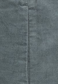 Un textile bleu foncé présentant une surface fine et texturée avec des lignes diagonales ; comprend des coutures visibles le long des bords.