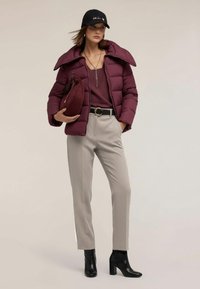 Vínová prošívaná bunda se širokým límcem, doplněná bordovým topem a béžovými kalhotami. Černé kotníkové boty a kšiltovka dotvářejí vzhled. Součástí je i psaníčko.