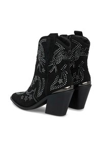 Botines de ante negro con diseños de tachuelas plateadas, punteras afiladas y tacones gruesos. Se pueden ver patrones detallados de estrellas y remolinos.