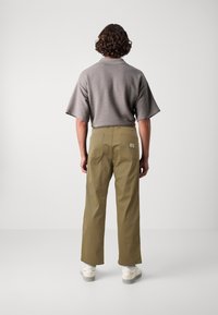 Grå, struktureret polo t-shirt med korte ærmer, kombineret med olivengrønne, lige bukser med baglommer og hvide sneakers.