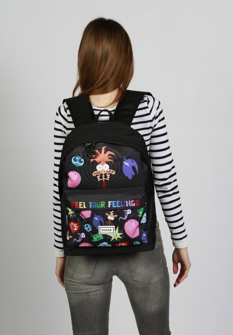 Mochila negra con estampados de personajes coloridos de Pixar, que incluye el texto "Siente tus sentimientos". Hecha de una tela duradera, con correas ajustables.
