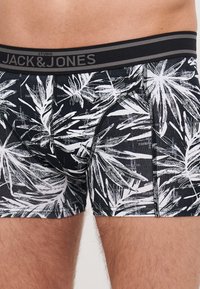 Boxer da uomo neri con motivo a foglia bianca, dotati di un elastico nero con il logo "JACK & JONES". Realizzati in un materiale morbido e elasticizzato.