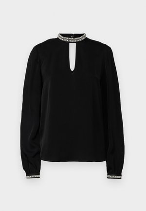 Blusa nera a maniche lunghe con collo alto e apertura a chiave, con polsini decorati e texture liscia. Accentuata da un colletto decorativo.