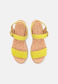 Sandalias de ante amarillas con dos correas anchas y cierre de hebilla. Las plantillas presentan un diseño de hojas sobre un fondo marrón claro.