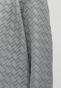 Κοντινό πλάνο γκρι υφάσματος με υφή, υφαντό ζιγκ ζαγκ σχέδιο και απαλή, παχιά εμφάνιση.