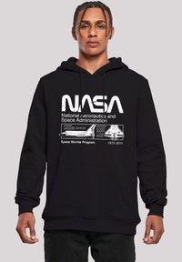 Black hoodie featuring white NASA graphics, including "National Aeronautics and Space Administration" and a Space Shuttle design with dates 1972-2011.