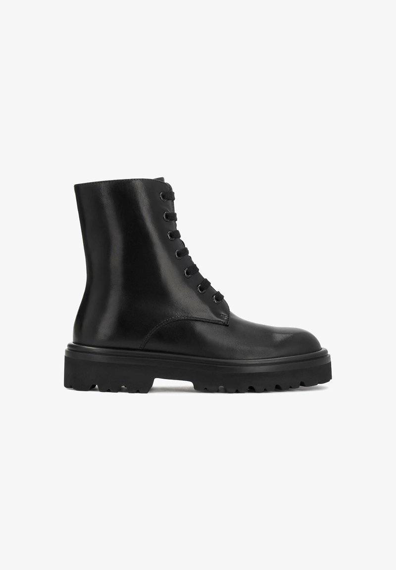 Bottine en cuir noir avec semelle épaisse crantée, bout rond et lacets sur le devant sur fond blanc.