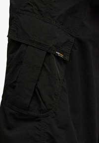 Camicia in tessuto nero con tasca cargo dotata di patta con chiusura in Velcro, etichetta CORDURA® e cuciture visibili per una maggiore durata.