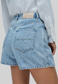 Shorts de mezclilla azul con un acabado ligeramente desgastado, que cuentan con una tela texturizada, dos bolsillos traseros y una etiqueta de cuero que dice "SALSA JEANS."