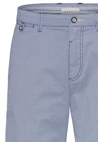 Pantalons bleus à motif en forme de diamant. Le matériau est du coton doux avec une fermeture éclair et des poches avant. Accents en métal doré visibles.