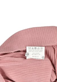 Tessuto a coste rosa che mette in evidenza una vita piegata, con un'etichetta di cura che mostra le istruzioni di lavaggio e i dettagli di produzione.