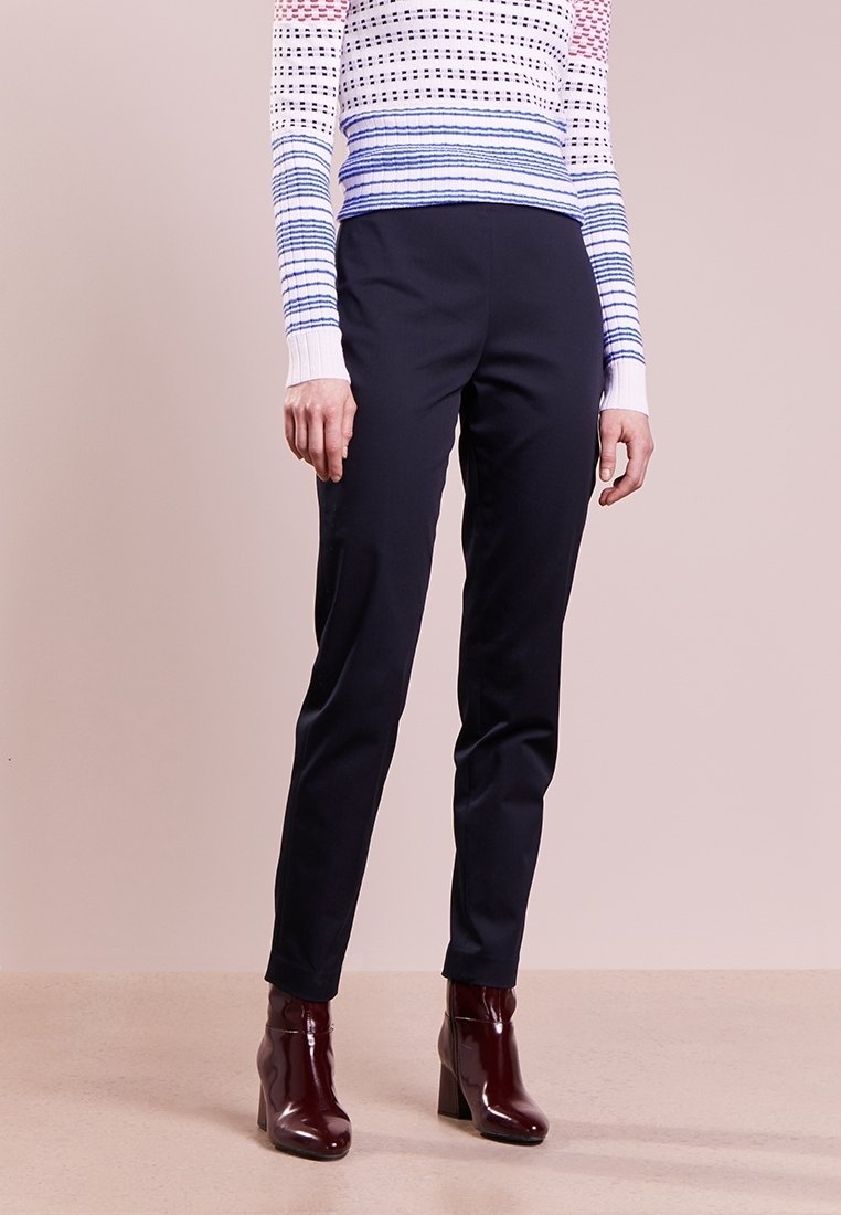 Marinblå skräddarsydda byxor i ett slätt tyg, med en smal passform och sidofickor, i kombination med bordeauxfärgade klackiga stövletter.