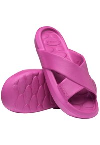 Pink rubber slide sandals with crossed strap design and textured footbed. Smooth surface and contoured shape for comfort.