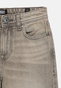 Γκρι τζιν υφασμένο από τζιν ύφασμα, με κλασικό σχέδιο πέντε τσεπών, μεταλλικό κουμπί κλεισίματος και διακριτική ξεθώριαση στη υφή του υφάσματος. Ετικέτα μεγέθους: 128.