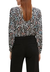 Langärmlige Bluse mit schwarzem Grund und einem bunten, abstrakten Muster. Der Stoff ist leicht, fließend und hat eine lockere Silhouette.