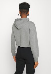 Cropped grey hoodie with a drawstring hood, long sleeves, and ribbed cuffs. Soft texture, paired with black pants.