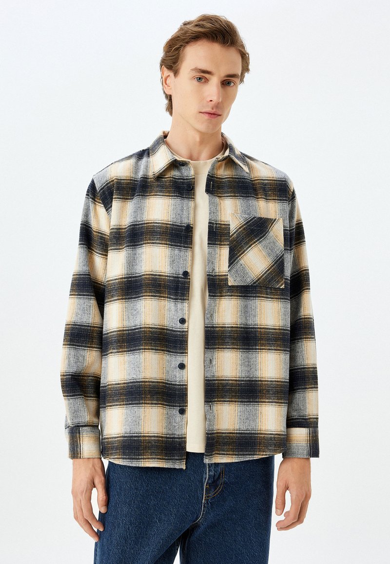 Plaid skjorte i beige, marineblå og sennepsfarvede nuancer med lange ærmer, knaplukning og en enkelt brystlomme. Fremstillet af flannel.