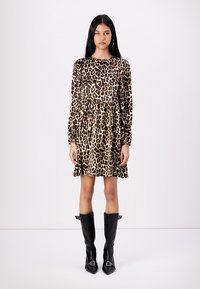 Φόρεμα με λεοπάρ μοτίβο, που διαθέτει μακριά μανίκια, συγκεντρωμένη μέση και φουσκωτή φούστα, σε συνδυασμό με μαύρες μπότες ως το γόνατο με μυτερή μύτη.