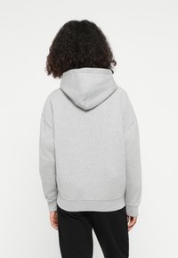 Grau kapuzenpullover mit lässiger Passform, ausgestattet mit einer Fleece-Oberfläche, gerippten Bündchen und Saum. Die Kapuze ist weich und leicht herunterhängend.