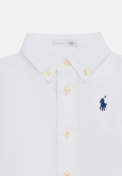 Λευκό γιακάς πουκαμίσου με κρεμ κουμπιά και κεντημένο λογότυπο παίκτη πόλο σε ναυτικό μπλε στο στήθος.