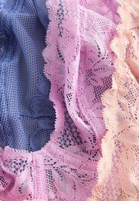 Blå, pink og ferskenfarvede blonder med blomsterprint lagdelt og draperet, der fremhæver indviklet mesh og bølgede kanter.