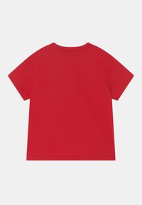 Červené tričko s krátkým rukávem vyrobené z bavlny. Má kulatý výstřih a jednobarevný design bez viditelných vzorů nebo akcentů.