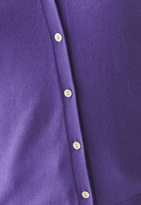 Purple knitted cardigan featuring a smooth texture, button-front closure with cream-colored buttons, and ribbed edges.
