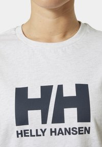 Camiseta de algodón gris claro con un gran logo en azul oscuro "HH" y el texto "HELLY HANSEN" debajo, con un clásico cuello redondo.